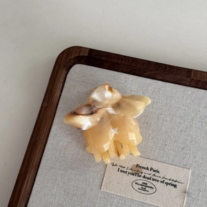 Gros plan d'une pince à cheveux fleur ambre crème avec des détails de texture acétate