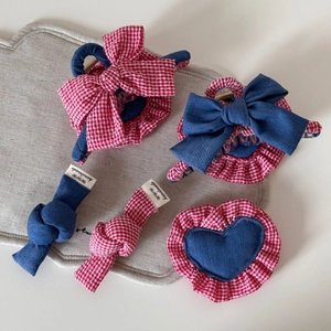 Detail of handmade denim and red plaid bow hair clips and scrunchies on linen mat