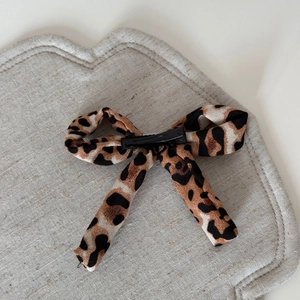 Detail of a leopard print fabric bow hair clip with a sturdy black alligator metal base