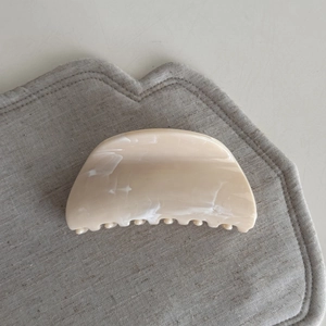 Close-up of cream marbled acetate hair claw clip with smooth curved design and strong teeth