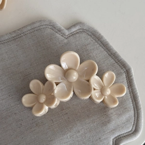 Detail of cream white triple frangipani flower hair claw clip with smooth resin finish
