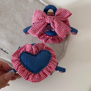 Detail shot of red checkered bow and denim heart hair clips with textured fabric details