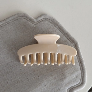 Macro shot of minimalist cream-colored resin shark hair claw clip with a polished finish