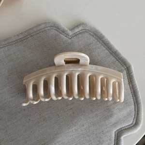 Detail view of large cream marble hair claw clip with golden metal spring for thick hair
