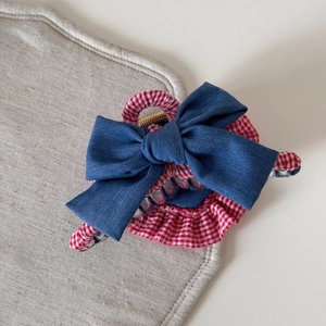 Detail showing denim bow and red gingham ruffles on a high-quality hair claw clip
