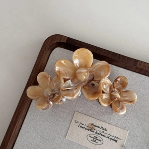 Détail d'une pince à cheveux fleurs avec texture ambre marbrée sur plateau lin