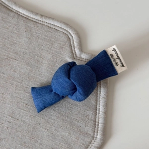 Detail of handmade blue denim hair clip featuring fabric texture and branded woven label