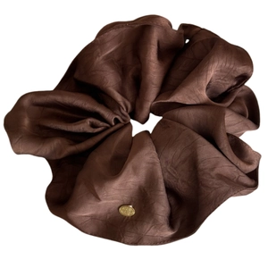 Dunkelbraunes Satin-Haargummi mit goldenem Metallanhänger und weicher Faltenstruktur