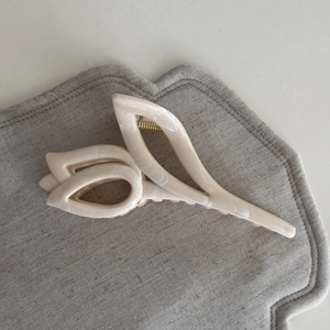Close-up of cream starfish flower hair claw clip with marble texture and gold spring