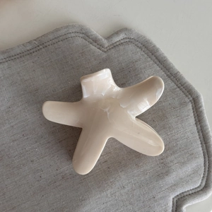 Detailed top view of cream starfish hair claw clip on neutral textured fabric