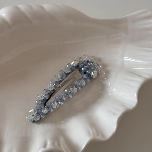 Détail d'une pince à cheveux en cristal bleu sur un plateau en coquillage