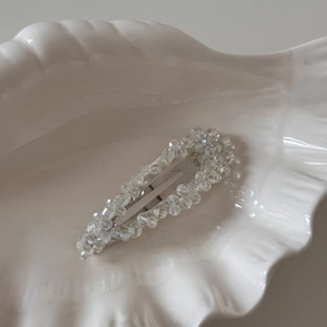 Vue détaillée des perles de cristal et de la pince à cheveux argentée sur un plateau