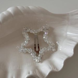 Gros plan d'une pince BB en cristal en forme d'étoile sur une coupelle blanche en coquillage