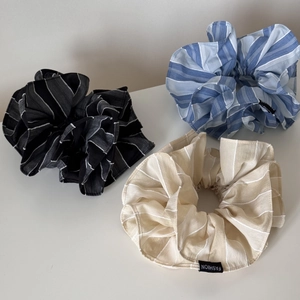Trois chouchous à rayures en gris, bleu et beige avec des étiquettes de mode noires