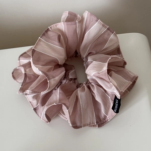Détail d'un chouchou rayé bicolore montrant la texture du tissu et l'étiquette
