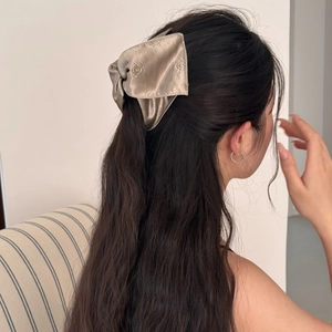 Detail of champagne satin bow hair claw clip with elegant rose embossed texture on hair