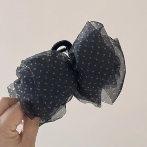 Détail de la pince à cheveux avec nœud en maille à pois noirs et tissu en mousseline