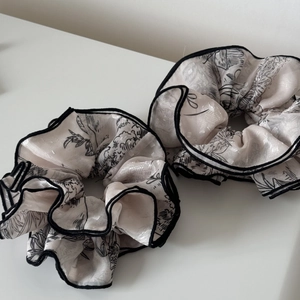 Detail of floral jacquard hair scrunchies with black stitched edges and elegant texture
