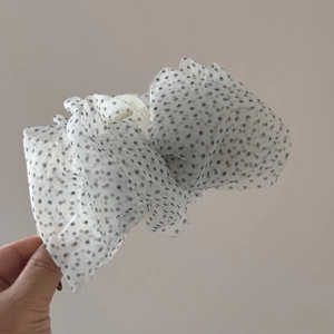 Détail de la grande pince à cheveux en organza blanc à pois noirs avec un design plissé