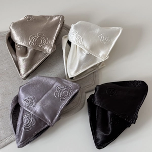 Detail of four-piece satin rose embossed hair claw clips in champagne and black colors