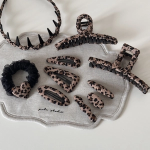 Brown leopard print hair accessory set with headband, claw clips, and hairpins on fabric