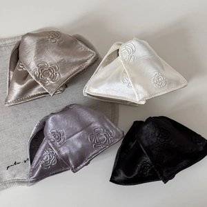 Close-up of embossed rose floral patterns on satin fabric hair clips in four elegant colors