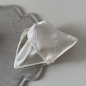 Detail of white satin fabric hair claw with embossed camellia floral pattern