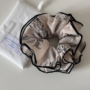 Detail of a large jacquard scrunchie with plant patterns and a cotton drawstring bag