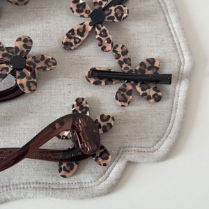 Gros plan sur des pinces à cheveux à fleurs léopard en résine marron sur un plateau