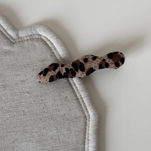 Close-up detail of leopard print fabric texture on a vintage style wavy hair claw clip