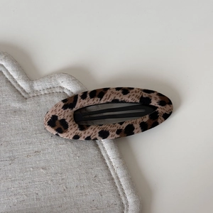 Close-up of leopard print fabric BB hair clip with oval design and black metal base