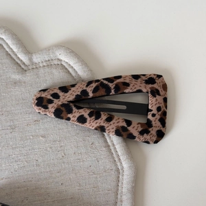 Close-up detail of leopard print fabric hair clip with soft texture on a white surface