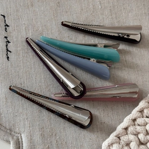 Gros plan de barrettes à cheveux en acétate de diverses couleurs sur fond de lin