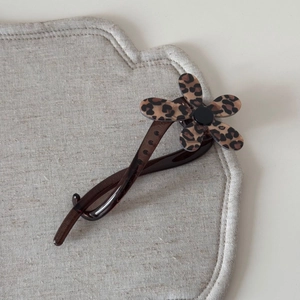 Vue détaillée d'une pince à cheveux à fleur léopard sur un fond en tissu de lin neutre
