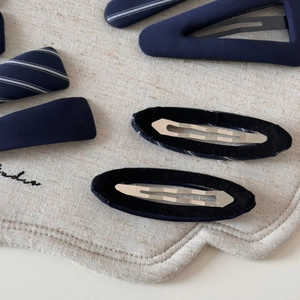 Detail of navy blue striped fabric hair clips with black velvet backing and metal grip