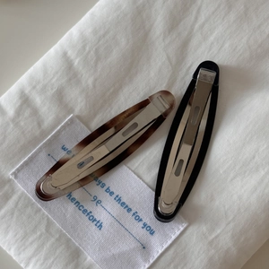 Detailed macro view of vintage tortoiseshell and black acetate hair clips on white fabric