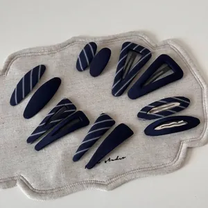 Navy blue striped hair clips set in oval and triangle shapes on a textured linen mat