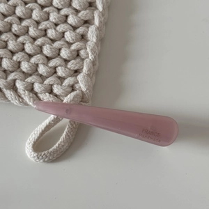 Détail d'une barrette en acétate rose avec logo doré France Handmade sur maille douce
