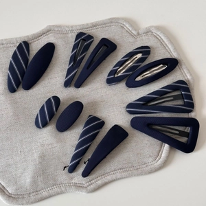 Detail view of navy blue striped hair clips in oval and triangle geometric shapes