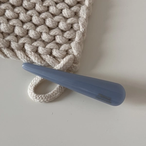 Gros plan sur la barrette à cheveux en acétate bleu Morandi avec gravure dorée