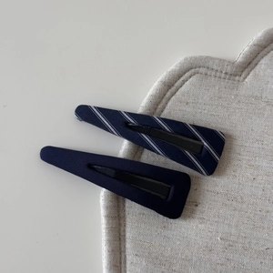 Detailed view of navy blue striped and solid fabric-wrapped BB hair clips on a linen mat