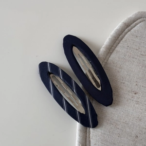 Detailed close-up of navy blue and white striped fabric oval hair clips for women