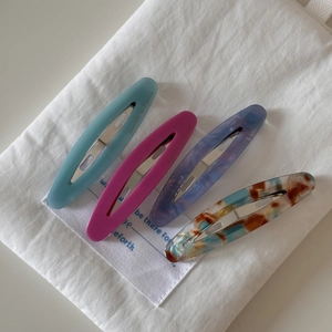 Detail view of four oval cellulose acetate barrettes on white cotton pouch
