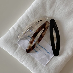 Detailed shot of three acetate barrettes in shell, pearl and black with French text