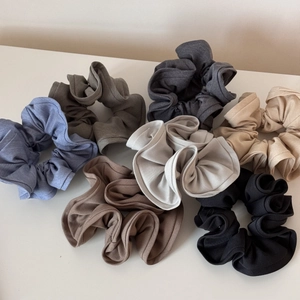 Detailed flat lay of seven soft fabric scrunchies in neutral earth tones and ruffled edges