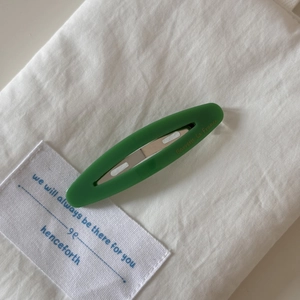 Detailed view of a French vintage green oval acetate barrette with metal spring clip