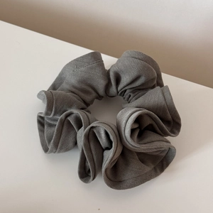 Detailed macro view of large taupe hair scrunchie with layered pleated fabric texture