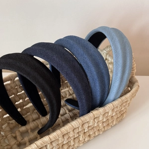 Detail of four padded denim headbands in blue and black colors in a woven basket