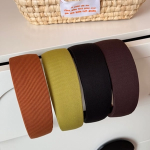 Détail de quatre serre-têtes rayés larges en orange, jaune, noir et marron foncé