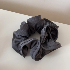 Detail view of deep grey pleated fabric scrunchie with textured twill finish and stitching